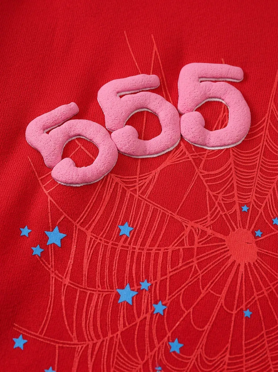 Pink foam numbers 555 pop against a red backdrop with subtle spiderwebs and blue stars, capturing the bold streetwear feel of the Red 555 Sp5der Hoodie – 440GSM Heavyweight Sp5der 555 Web Oversized Pullover.