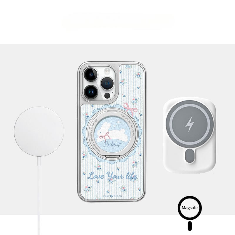 A charming smartphone case featuring a 蓝色碎花小兔 and the text "Love Your Life," perfectly complements the Apple 16 Pro Max. It includes a built-in magnetic stand and SGS-certified drop protection for seamless connectivity, complete with a MagSafe charger pad.