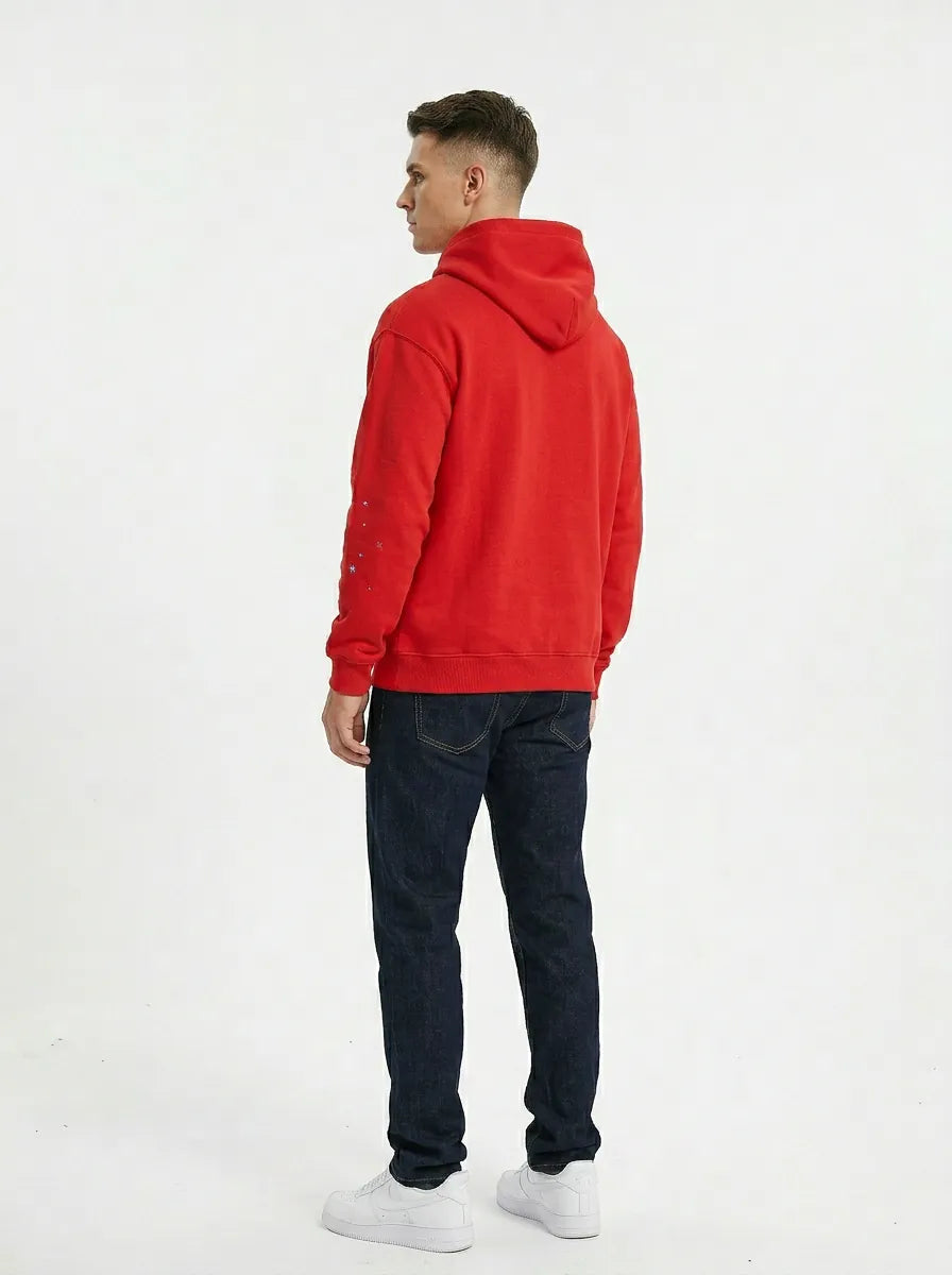 A man faces away, wearing the Red 555 Sp5der Hoodie – a 440GSM heavyweight web oversized pullover – with dark jeans and white sneakers, against a plain white background for a modern streetwear look.