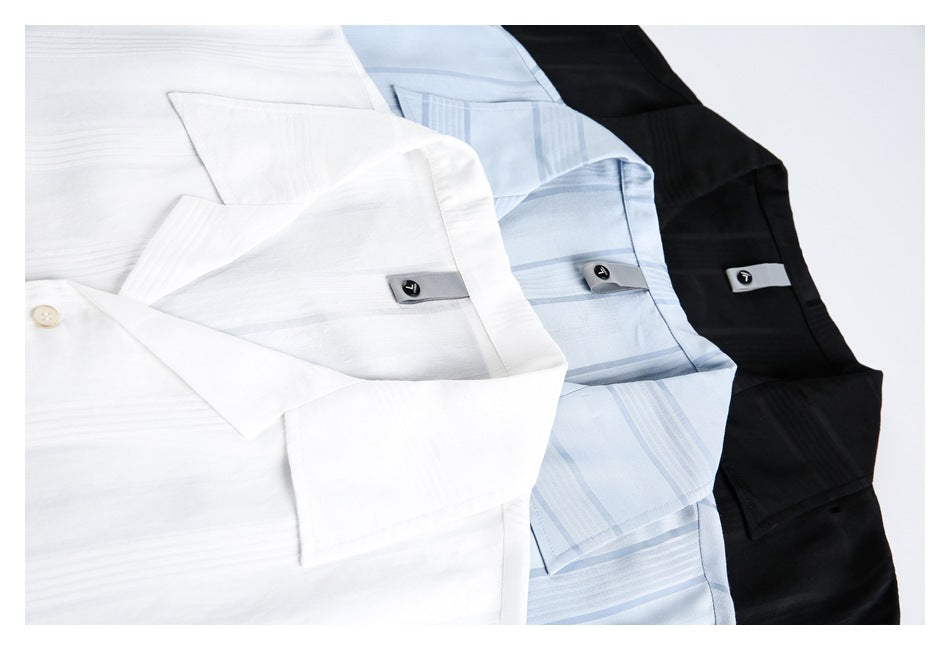 Close-up of white, pale blue striped, and black collared shirts arranged together, showing collars and button details.
