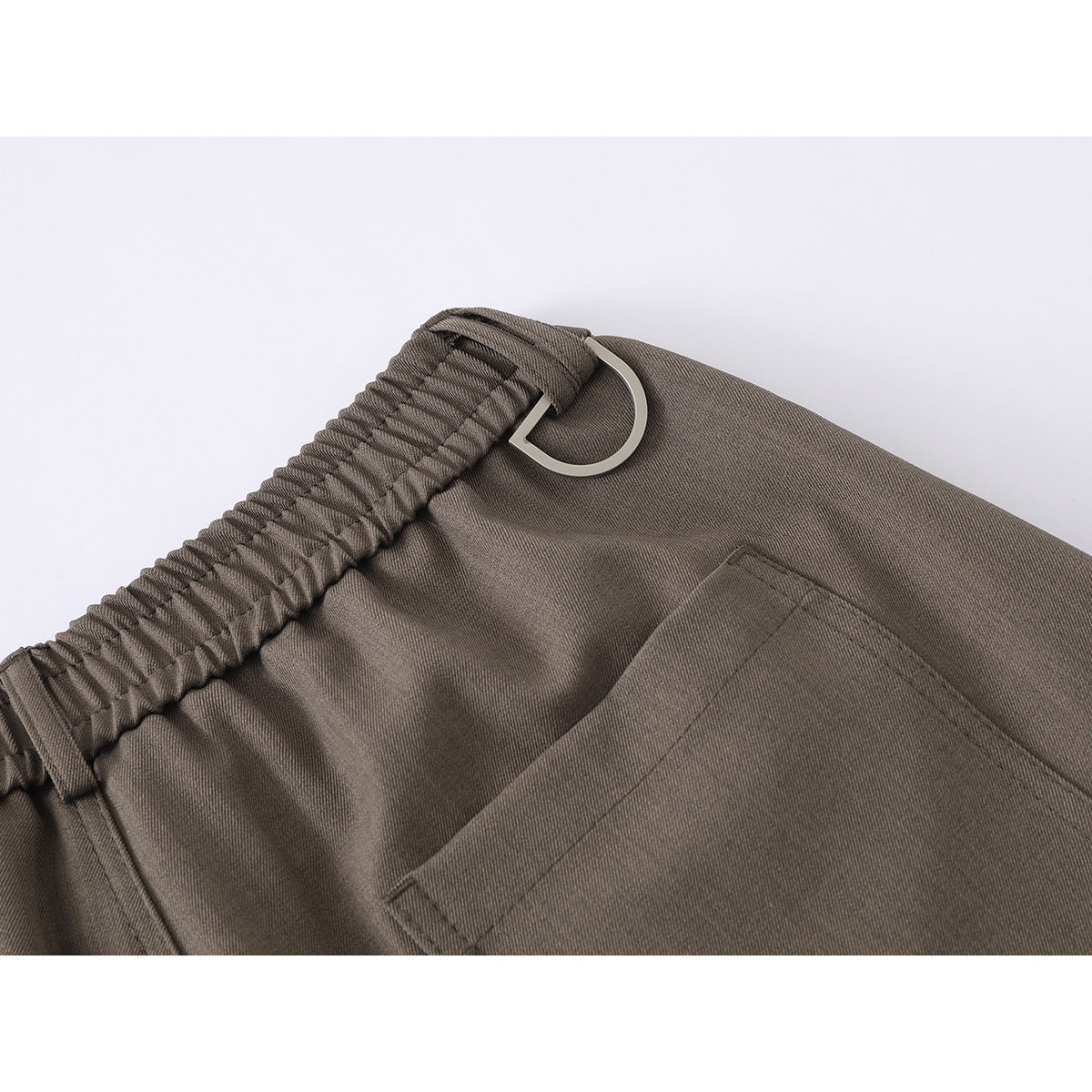 Close-up of the taupe shorts' elastic back waistband, metal loop, and rear pocket.
