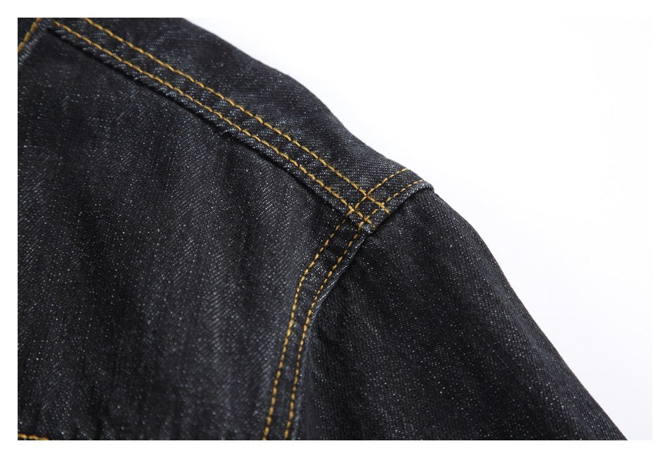 Close-up of a dark denim jacket shoulder seam with double rows of gold stitching.