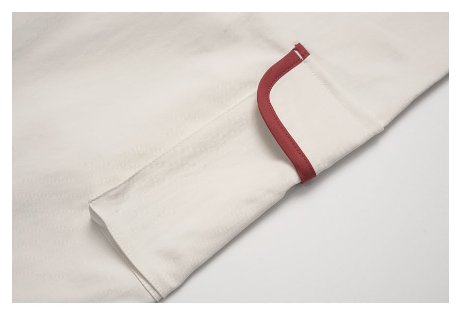 Close-up of a cream sleeve or panel with curved muted red trim.