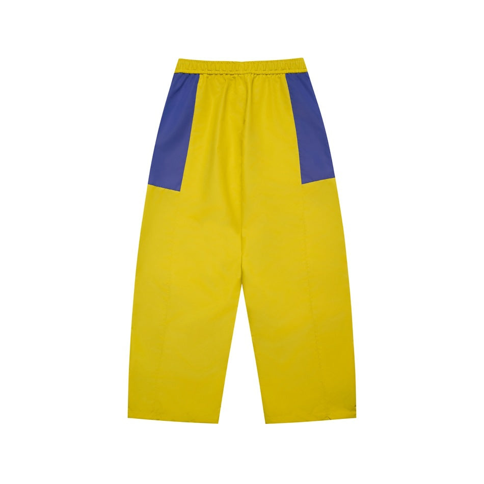 Back view of yellow pants with purple upper side panels and an elastic waistband.