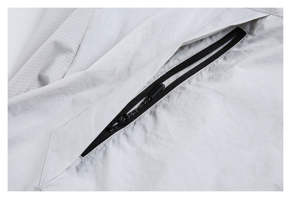 Close-up of a black zippered pocket on a light gray jacket, with the zipper partly concealed by a flap.