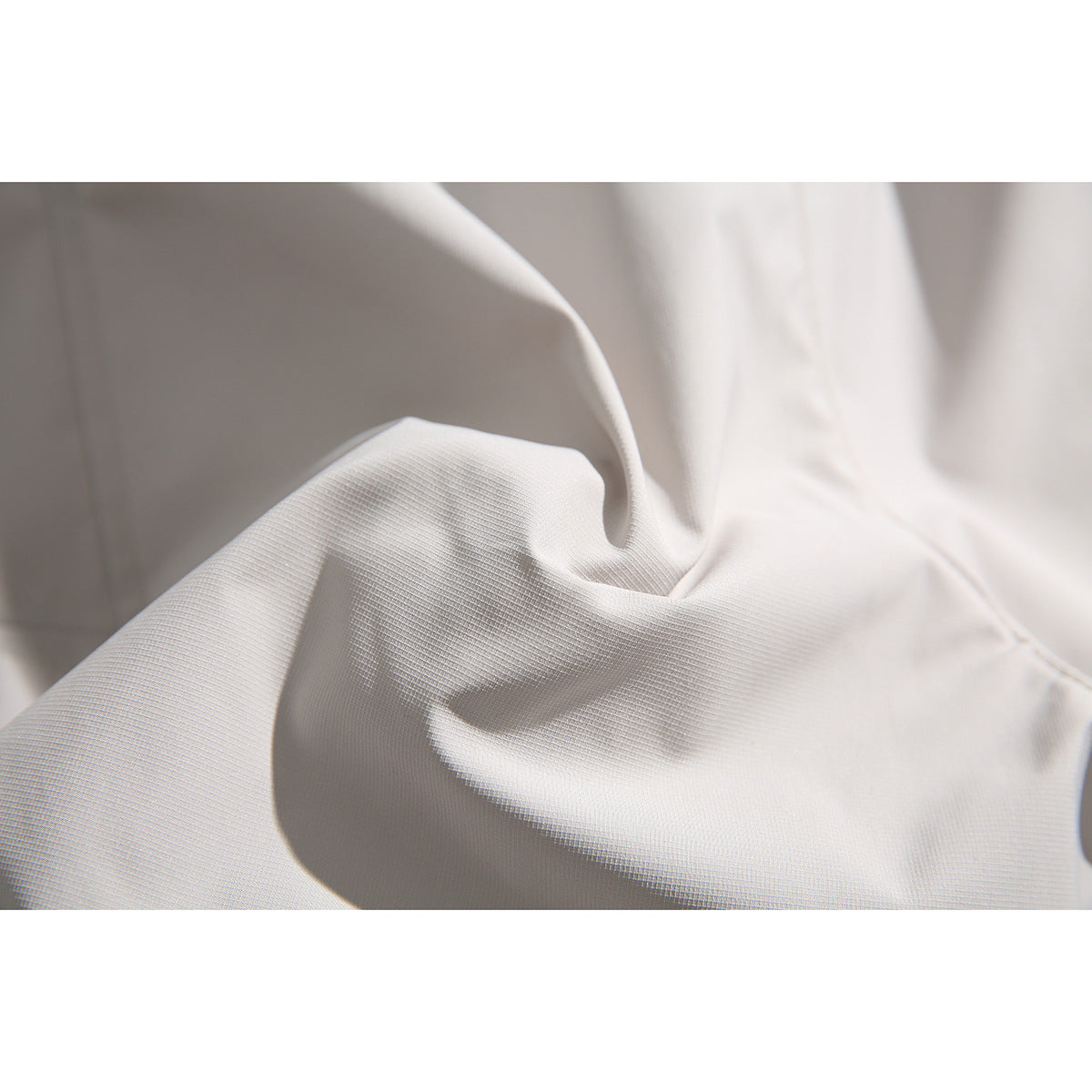 Extreme close-up of the light gray shorts fabric, showing its fine texture and folds.