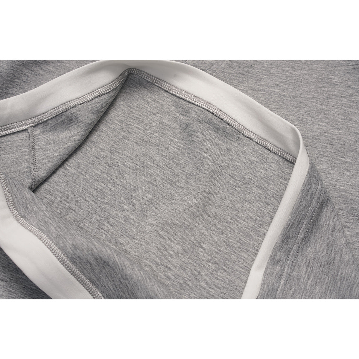 Close-up of the inside seam and white trim along the hem of a light gray top.