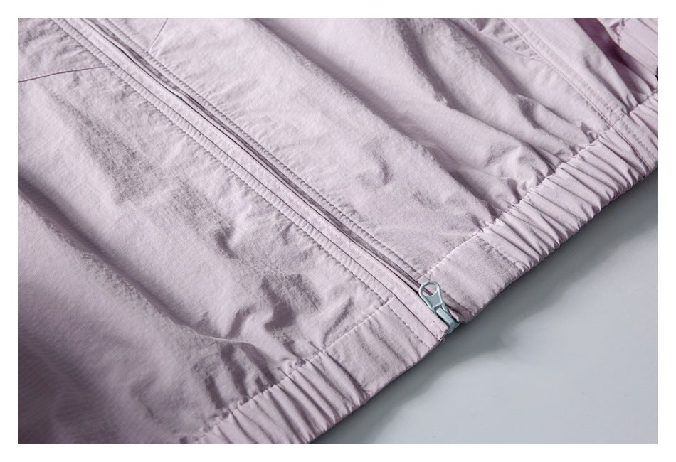 Close-up of the pale lavender jacket’s front zipper and gathered elastic hem, with a light blue zipper pull.