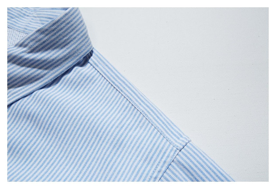 Close-up of a white shirt with fine blue stripes, showing the collar and shoulder seam.
