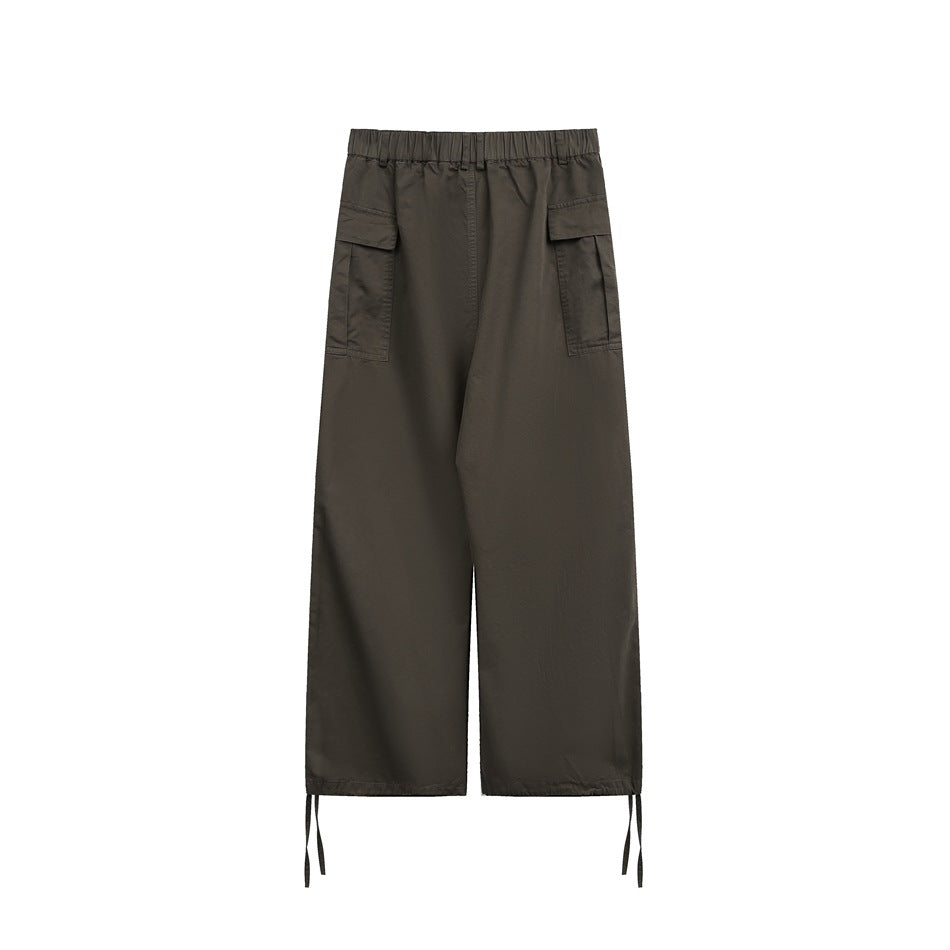 Rear view of dark olive wide-leg cargo pants with flap pockets and adjustable ties at the hems.