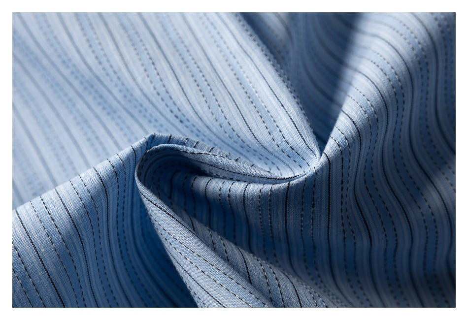 Close-up of softly folded light blue fabric with narrow dark vertical stripes and visible stitching.
