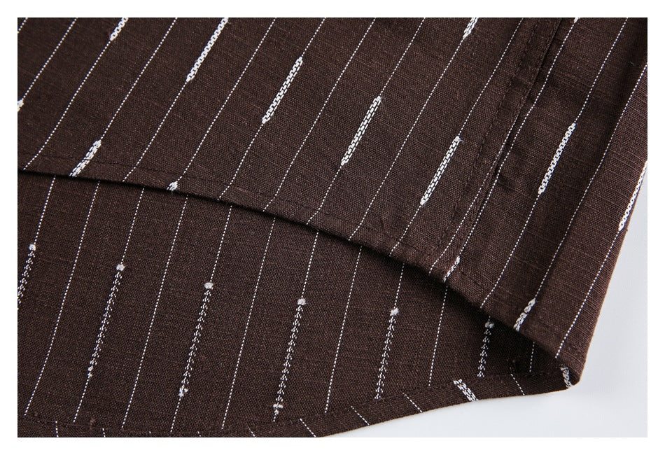 Close-up of a folded and stitched edge on brown fabric with thin white dashed stripes.