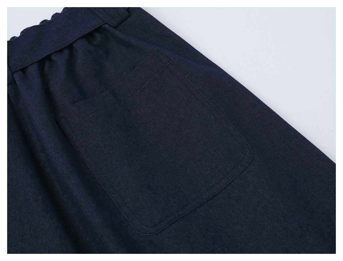 Close-up of a large stitched patch pocket on dark navy trousers.