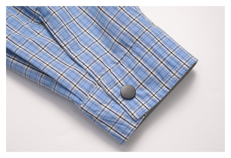 Close-up of a blue plaid sleeve cuff with a large dark button.