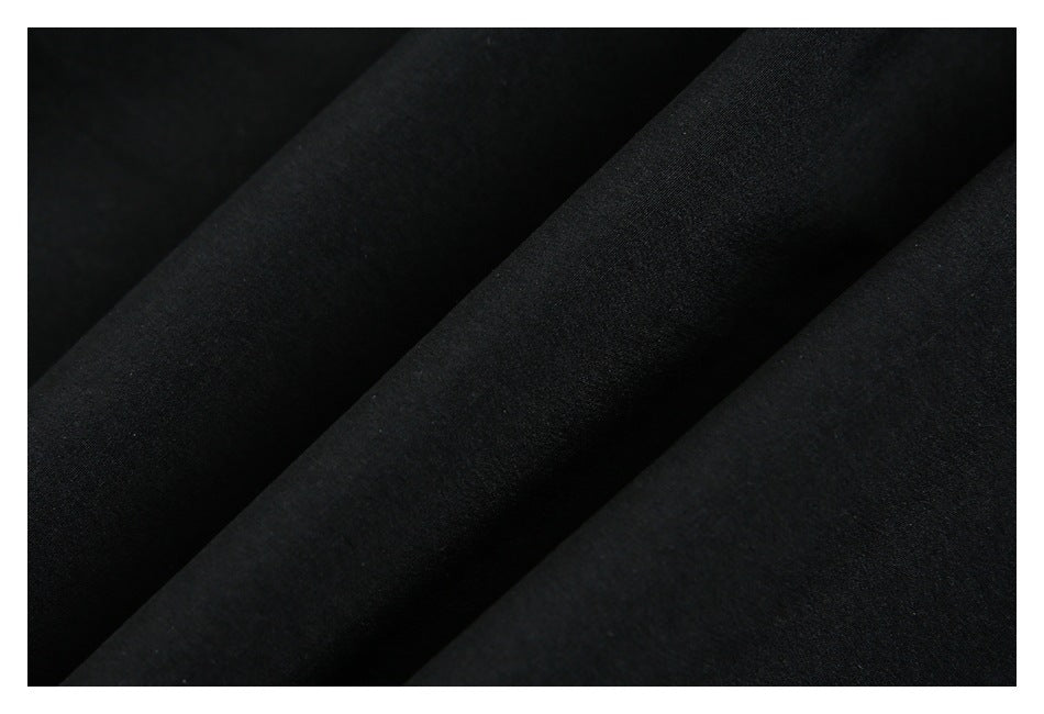 Close-up of black fabric arranged in soft diagonal folds, showing a fine textured surface.