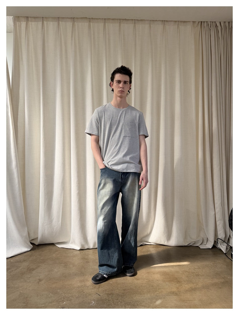 Full-length model wearing a gray finely striped pocket T-shirt and wide-leg blue jeans.