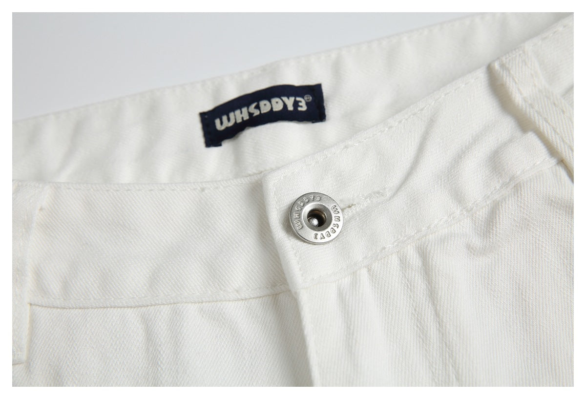 Close-up of white pants’ waistband, metal button, and sewn-in dark brand label.