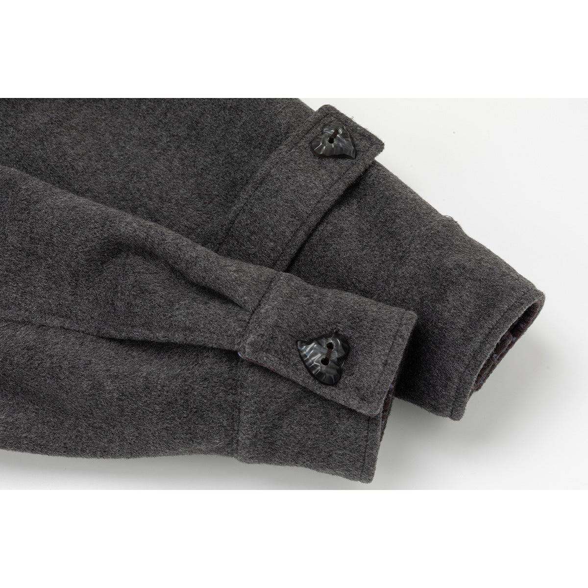Close-up of a charcoal coat sleeve with a cuff tab and heart-shaped button.