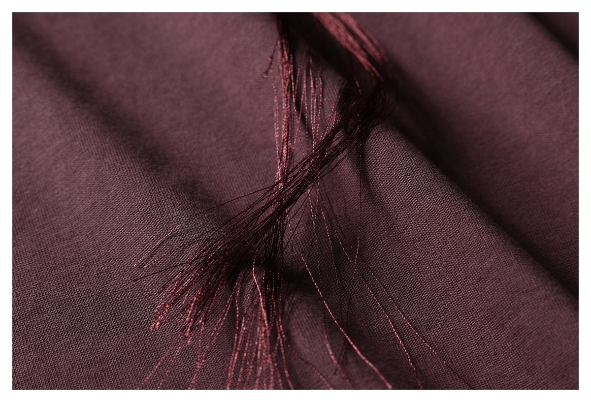 Close-up of dark burgundy fabric with loose dark and burgundy embroidery threads.