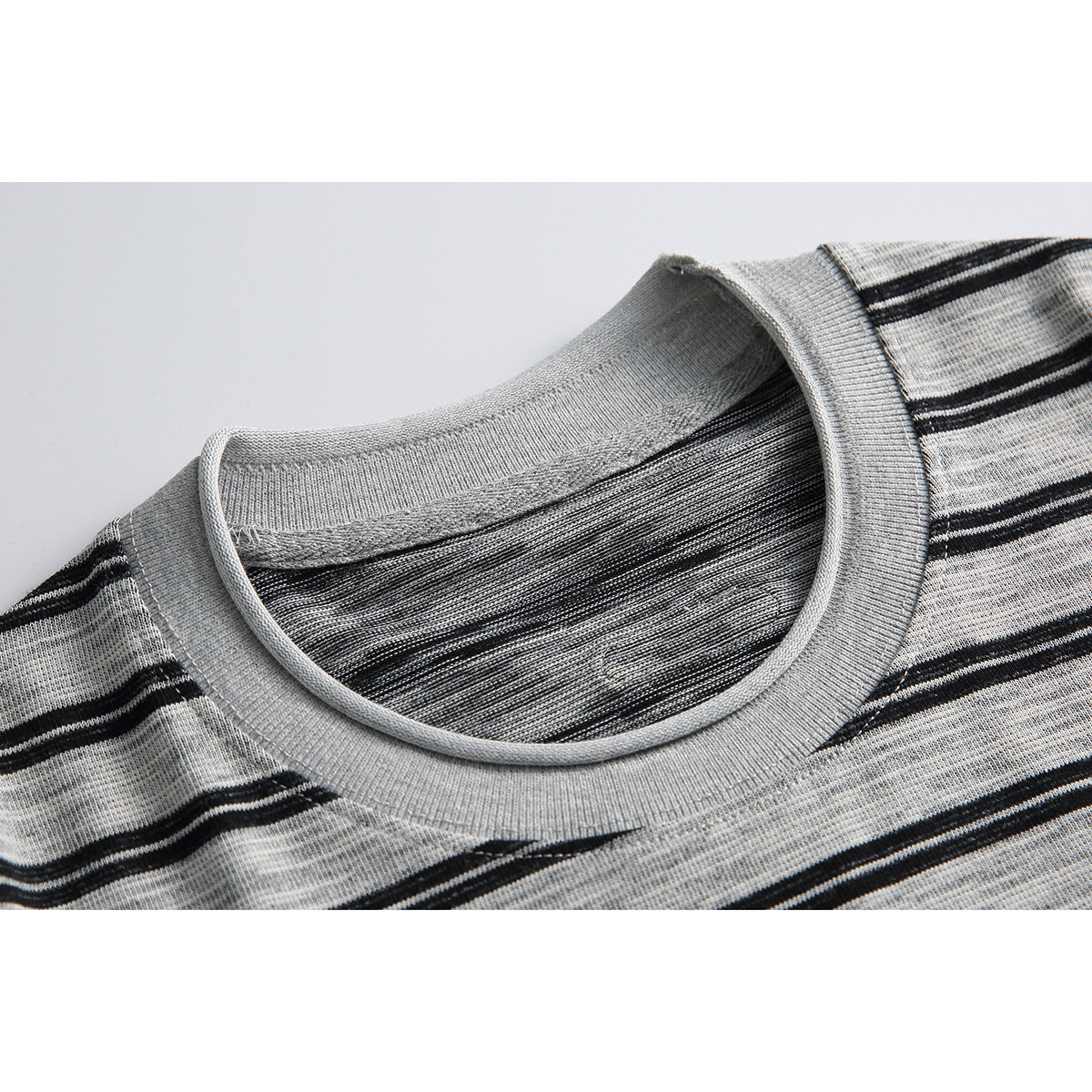 Close-up of a light gray ribbed crew neck and black horizontal stripes on a shirt.