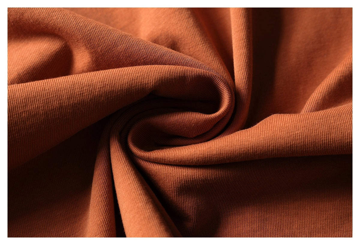 Close-up of rust-orange fabric gathered into folds, showing its fine knit texture.