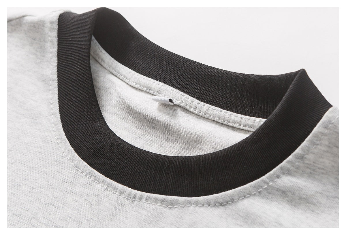 Close-up of a light gray melange shirt with a wide black ribbed crew neckline and visible stitching.