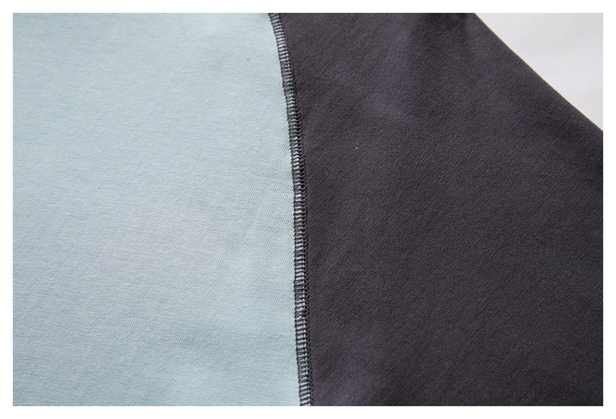Close-up of pale blue and charcoal fabric panels joined by a dark overlock seam.