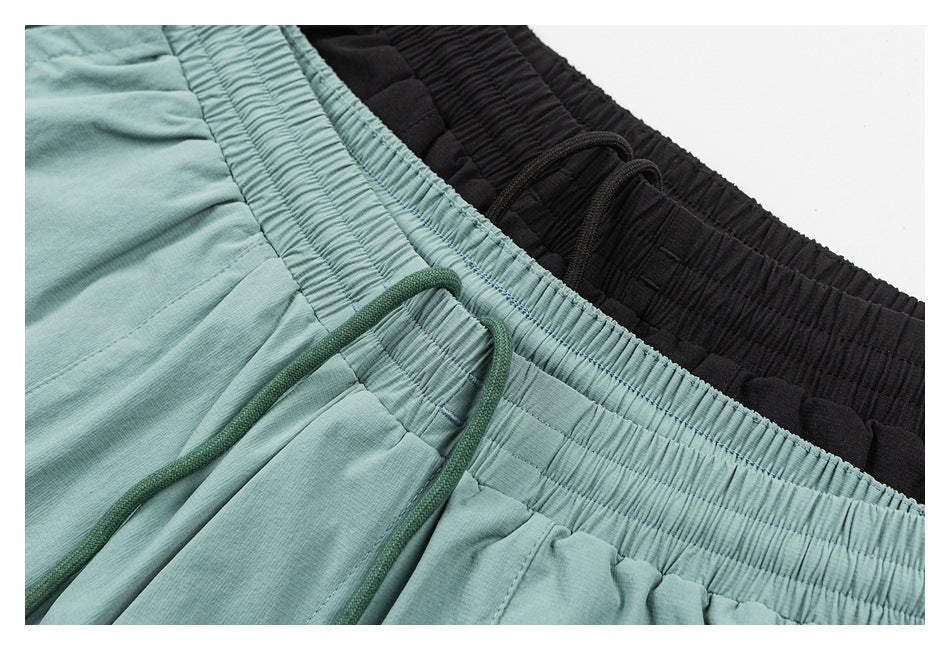 Close-up of mint-green and black shorts showing gathered elastic waistbands and drawstrings.