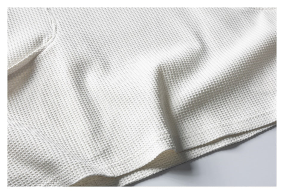 Close-up of the off-white textured garment fabric and finished hem.