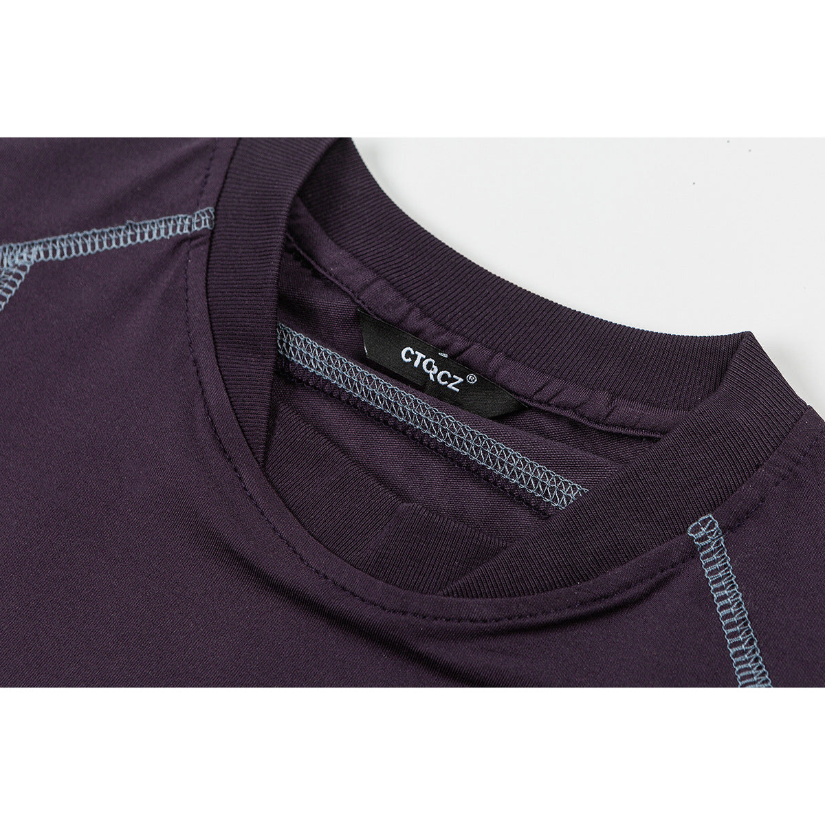 Close-up of the plum shirt’s ribbed crew neck, inner label and contrast shoulder stitching.