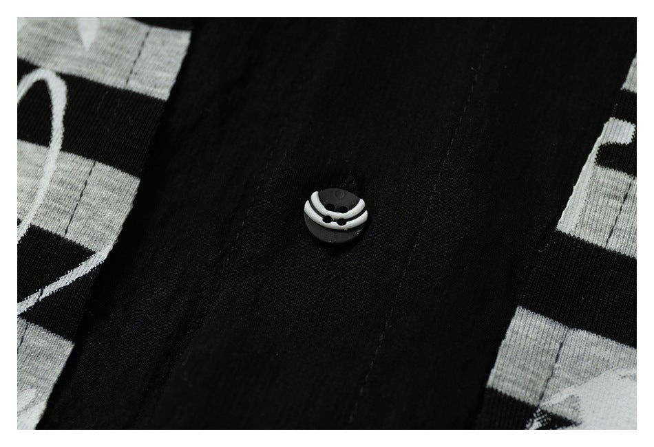 Close-up of a black placket with a small black-and-white button against black and gray striped fabric.