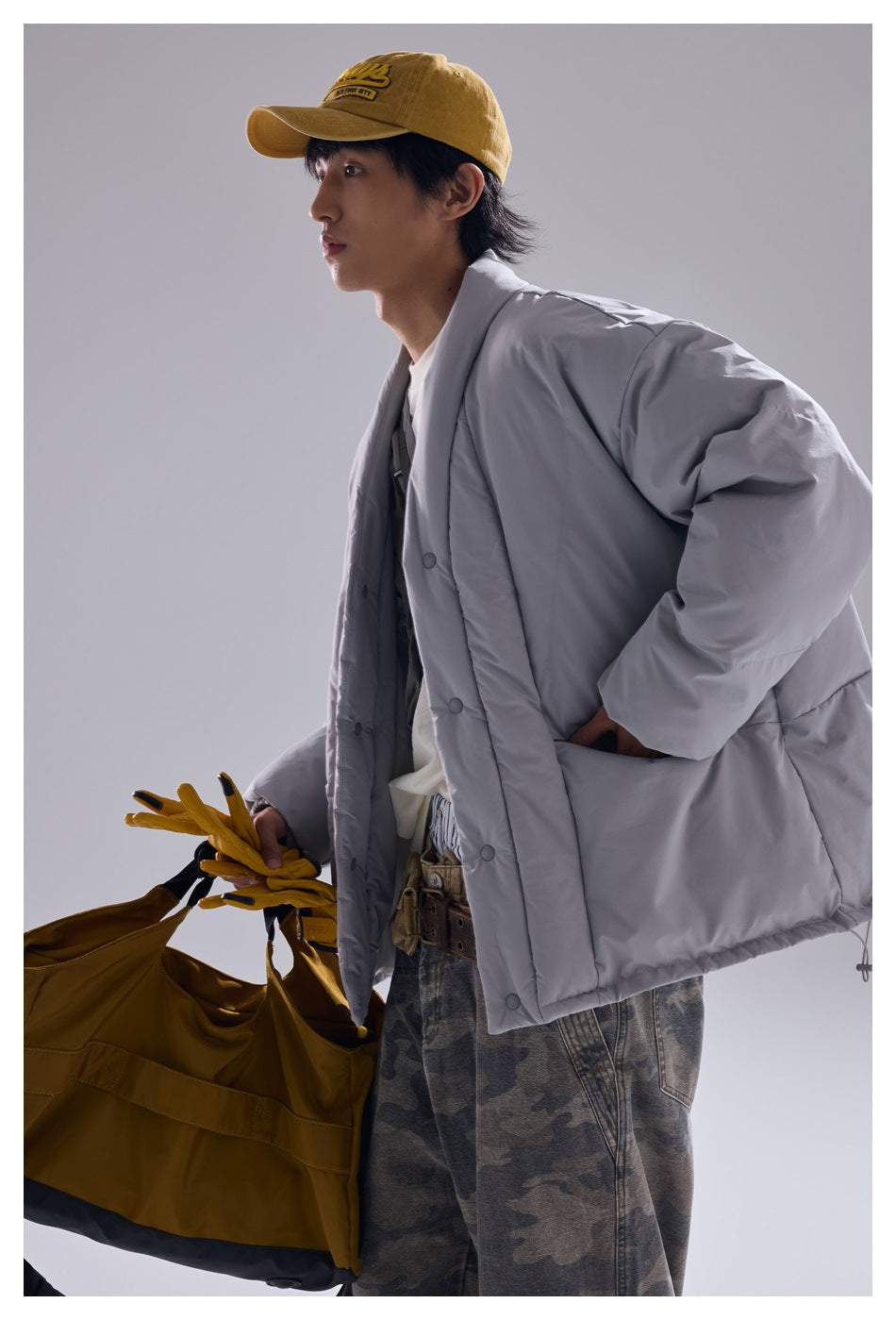 Model wearing an oversized light gray snap-front quilted jacket with dropped shoulders and large front pockets.