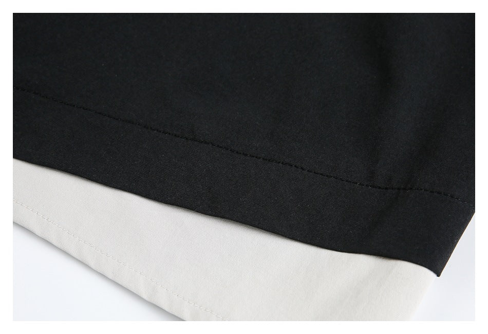 Close-up of the black and cream layered trouser hem with visible stitching.