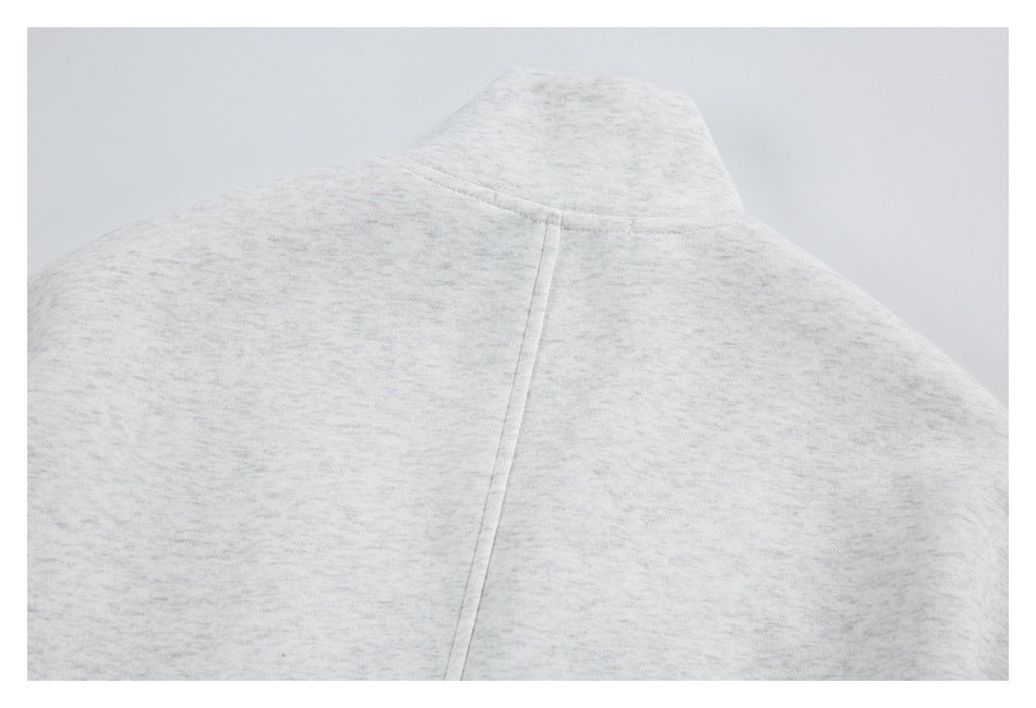 Close-up of light gray marl garment fabric with a raised collar edge and a vertical seam.