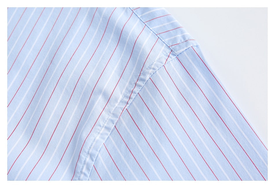 Close-up of a light blue shirt’s striped shoulder and sleeve seam.
