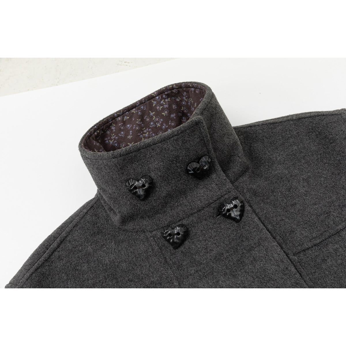 Close-up of the coat's high collar, floral-patterned inner lining, and glossy heart-shaped buttons.