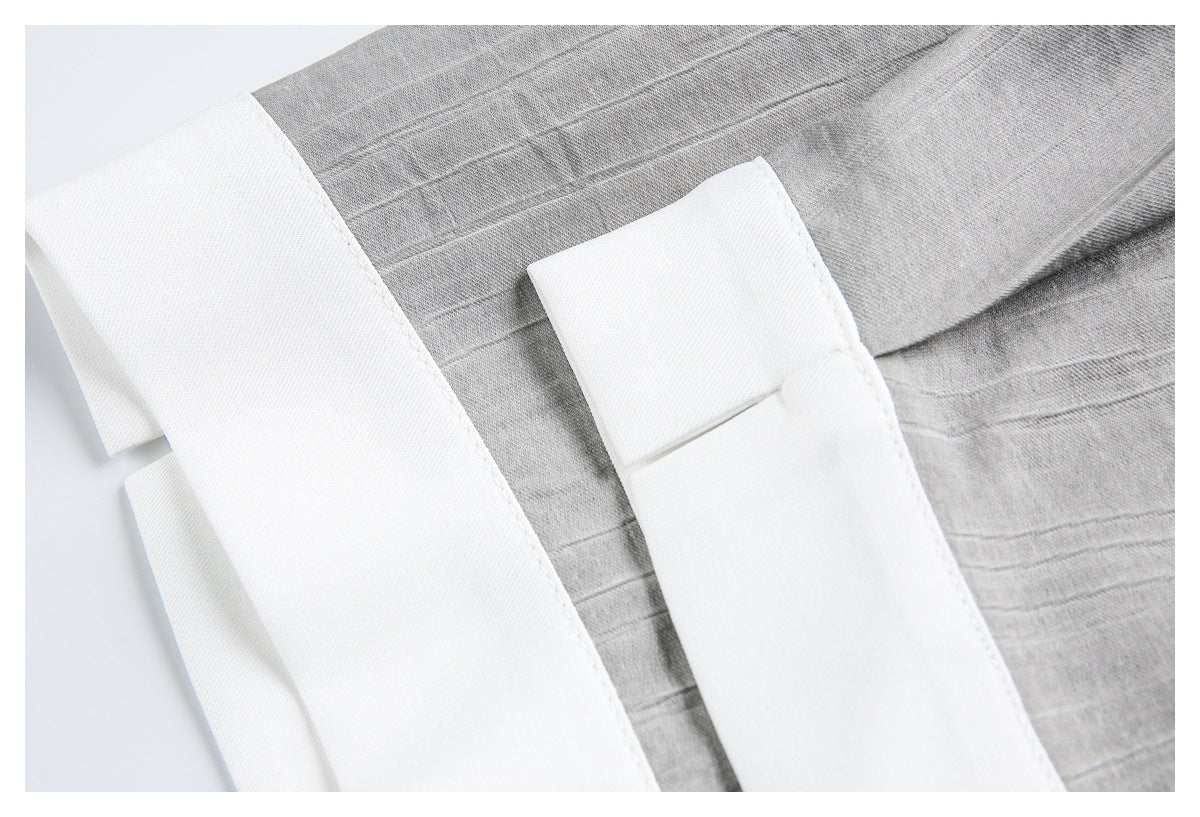 Close-up of gray striped fabric beside broad white bands and a small white fabric tab.