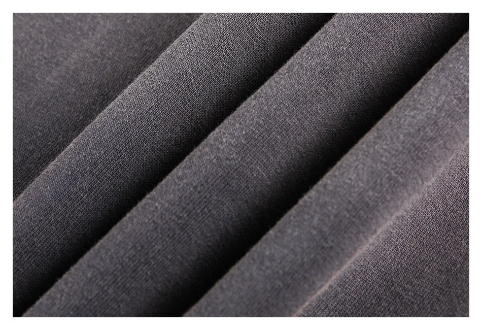 Macro view of charcoal-brown garment fabric arranged in folds.