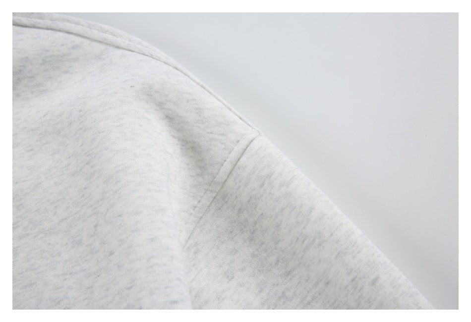 Close-up of the shoulder seam and sleeve construction on a light gray marled jacket.