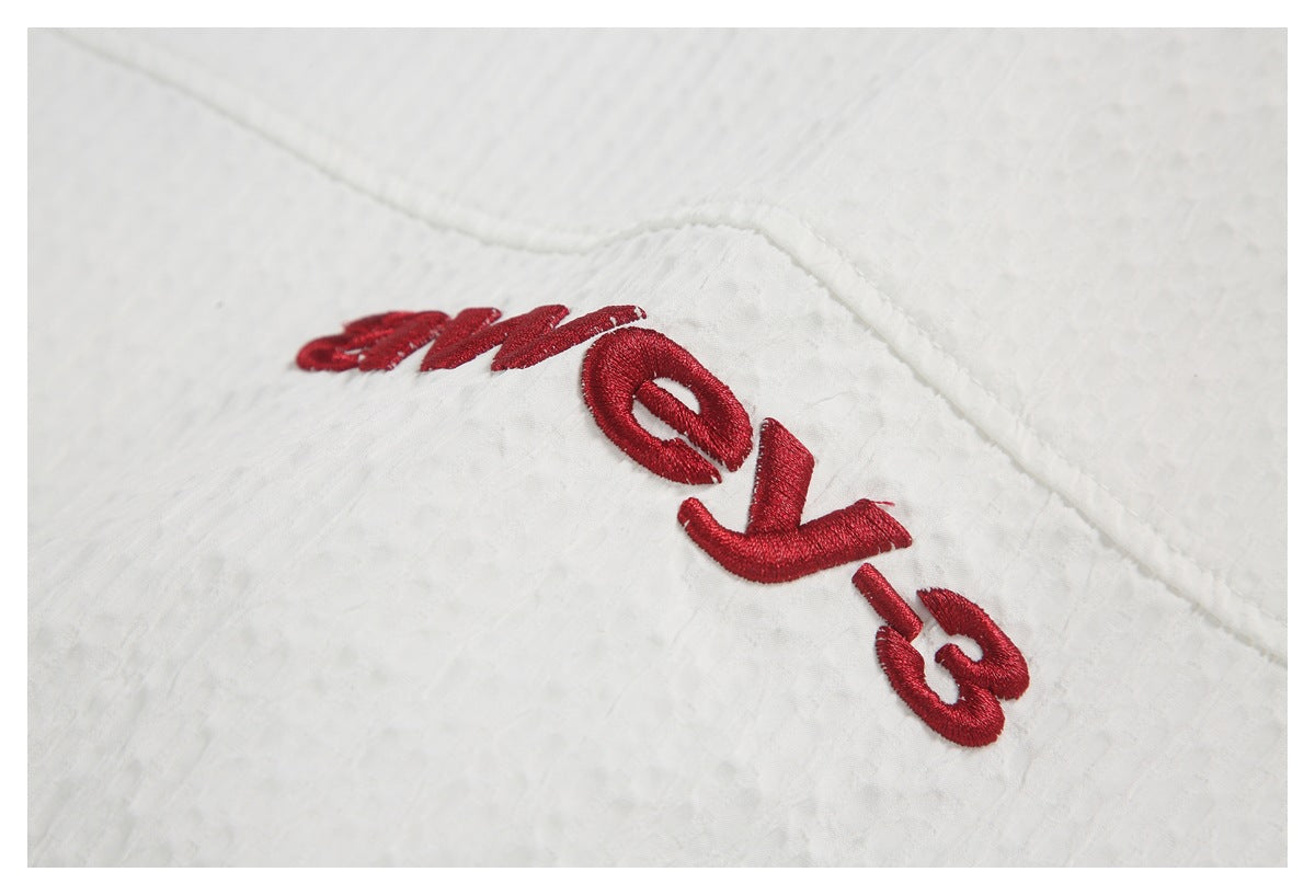 White textured fabric close-up with red embroidered lettering.