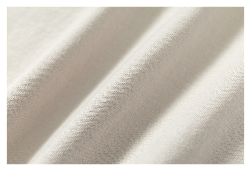 Extreme close-up of the ivory garment fabric, showing its surface and folds.