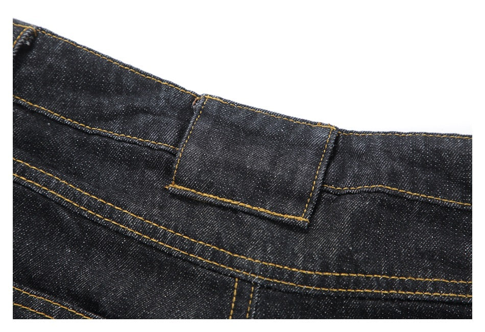 Close-up of a belt loop and waistband stitching on black denim trousers.