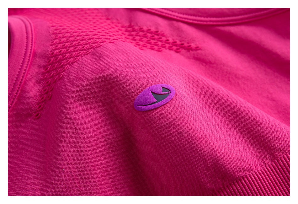 Close-up of a magenta garment with a small purple emblem, textured knit panels, and a ribbed edge.