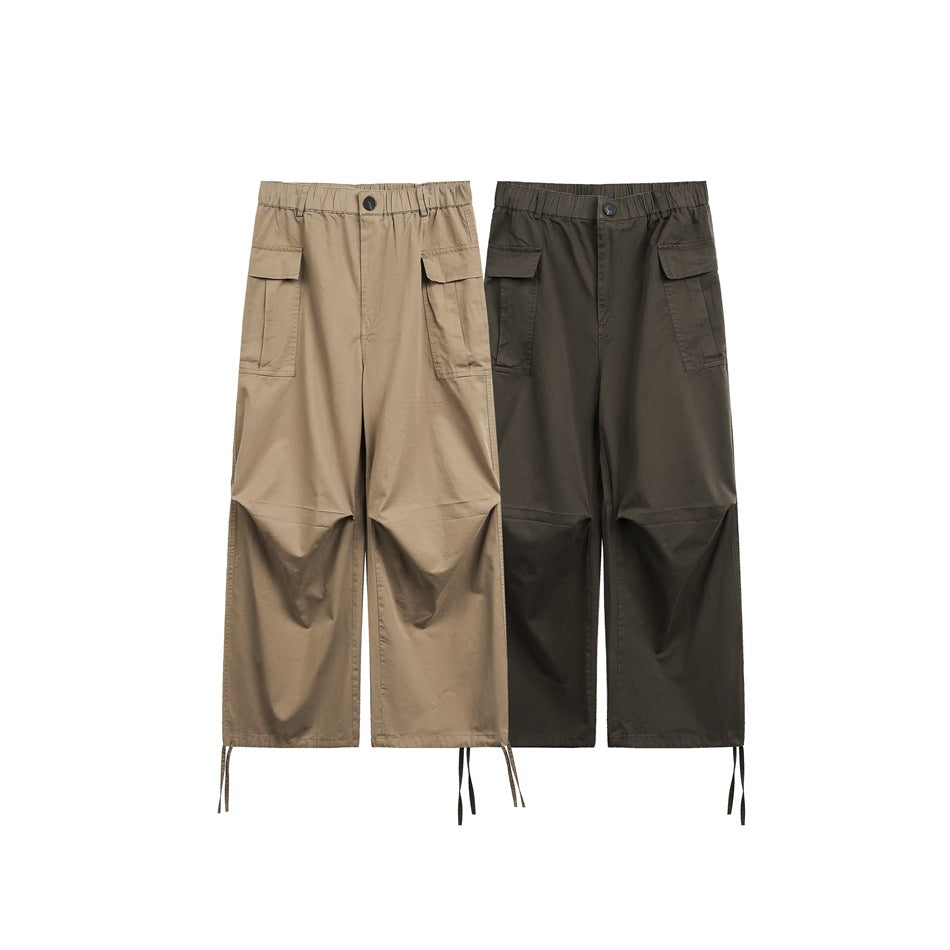 Tan and dark olive wide-leg cargo pants shown from the front with flap pockets and hem ties.