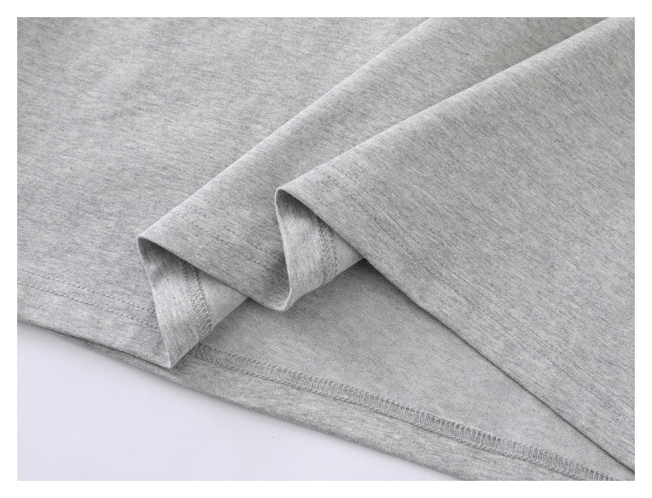 Close-up of the folded hem and stitching on a heather gray T-shirt.