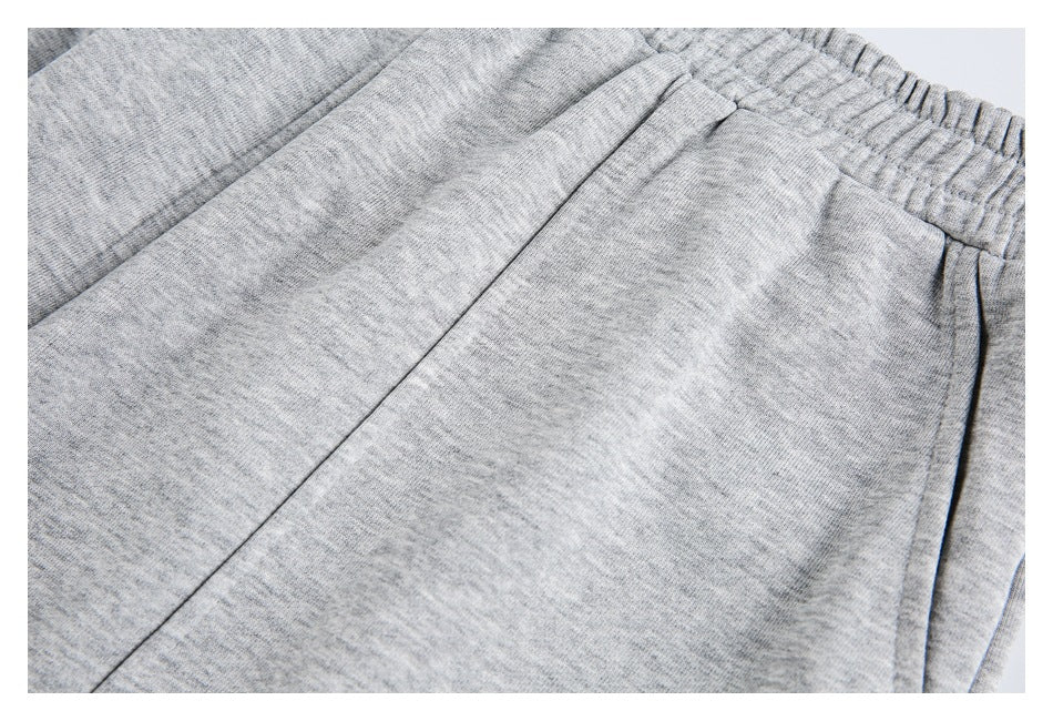 Close-up of light gray heather sweatpants with the elastic waistband, seams, and pocket edge visible.