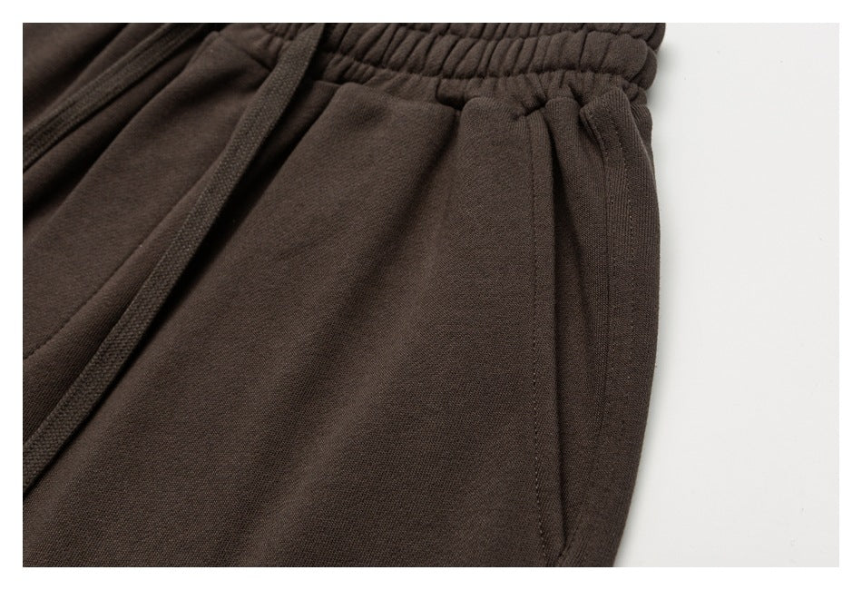 Close-up of dark brown sweatpants showing the side pocket and gathered elastic waistband.