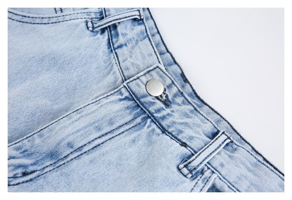 Close-up of light-wash jeans showing the metal waistband button, belt loop, and pocket seam.