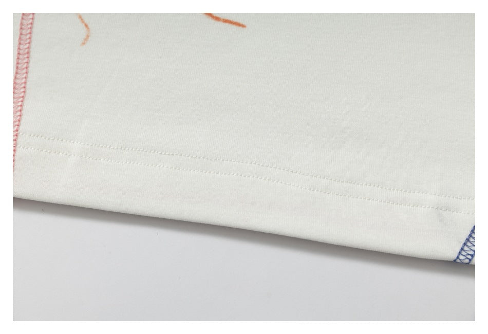 Close-up of the white shirt's bottom hem with straight stitching and a blue overlocked side seam.