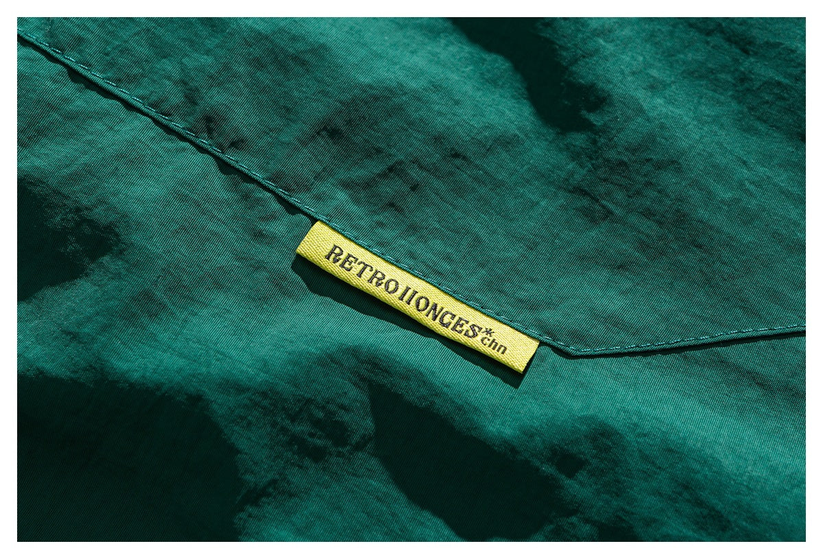 Close-up of a yellow woven label sewn onto teal-green fabric beside a stitched seam.